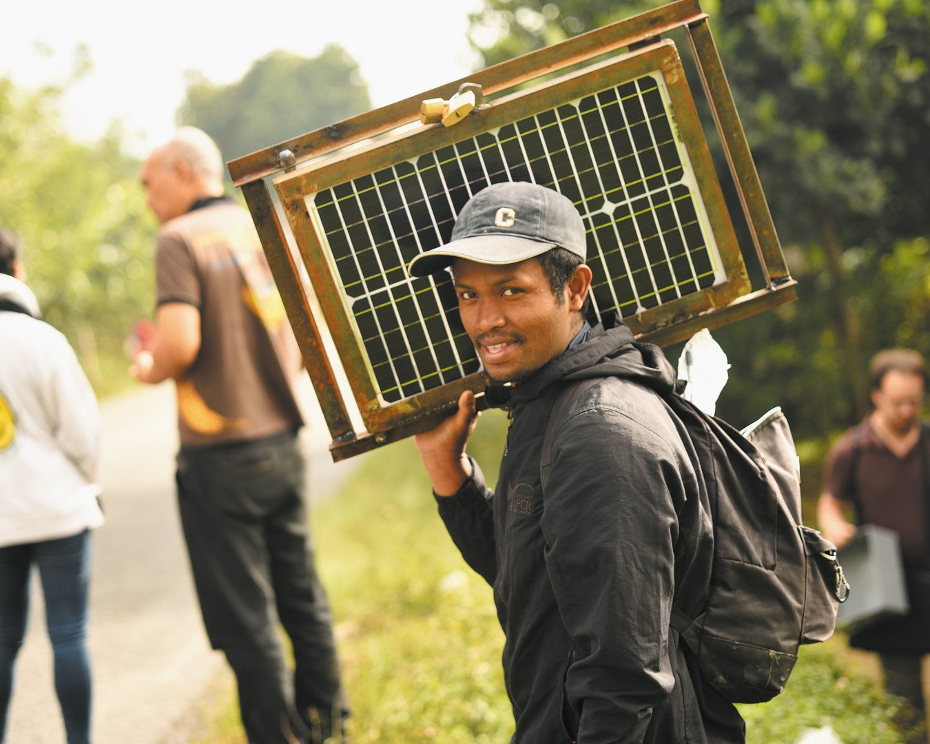 In a food distribution hut, a female nursing student talks with a Malagasy mother and children in brightly colored dresses