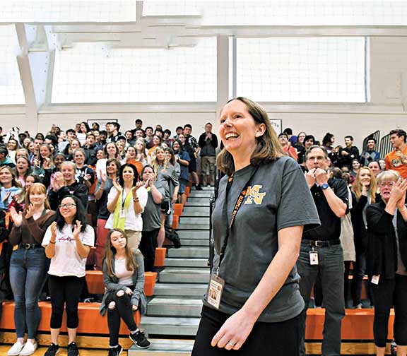 Elizabeth Landes receives a standing ovation from a crowd of students and teachers cheering in the bleachers