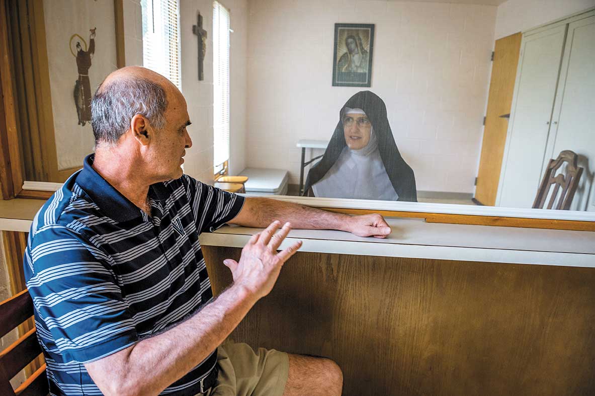 Sister Rose Marie, wearing her full religious habit, has a visit with Harry Perretta through a transparent screen 