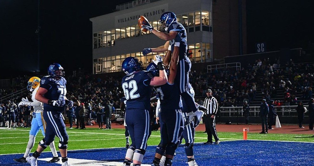 Football Two Villanova Football players holding up a team mate with the football in the end zone at Villanova Stadium