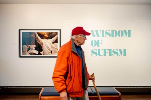 Older man walking in front of the Wisdom of Sufism exhibit