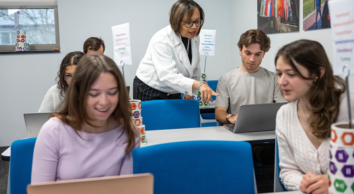personal-professional-home Students working together on laptops with staff member providing guidance in background