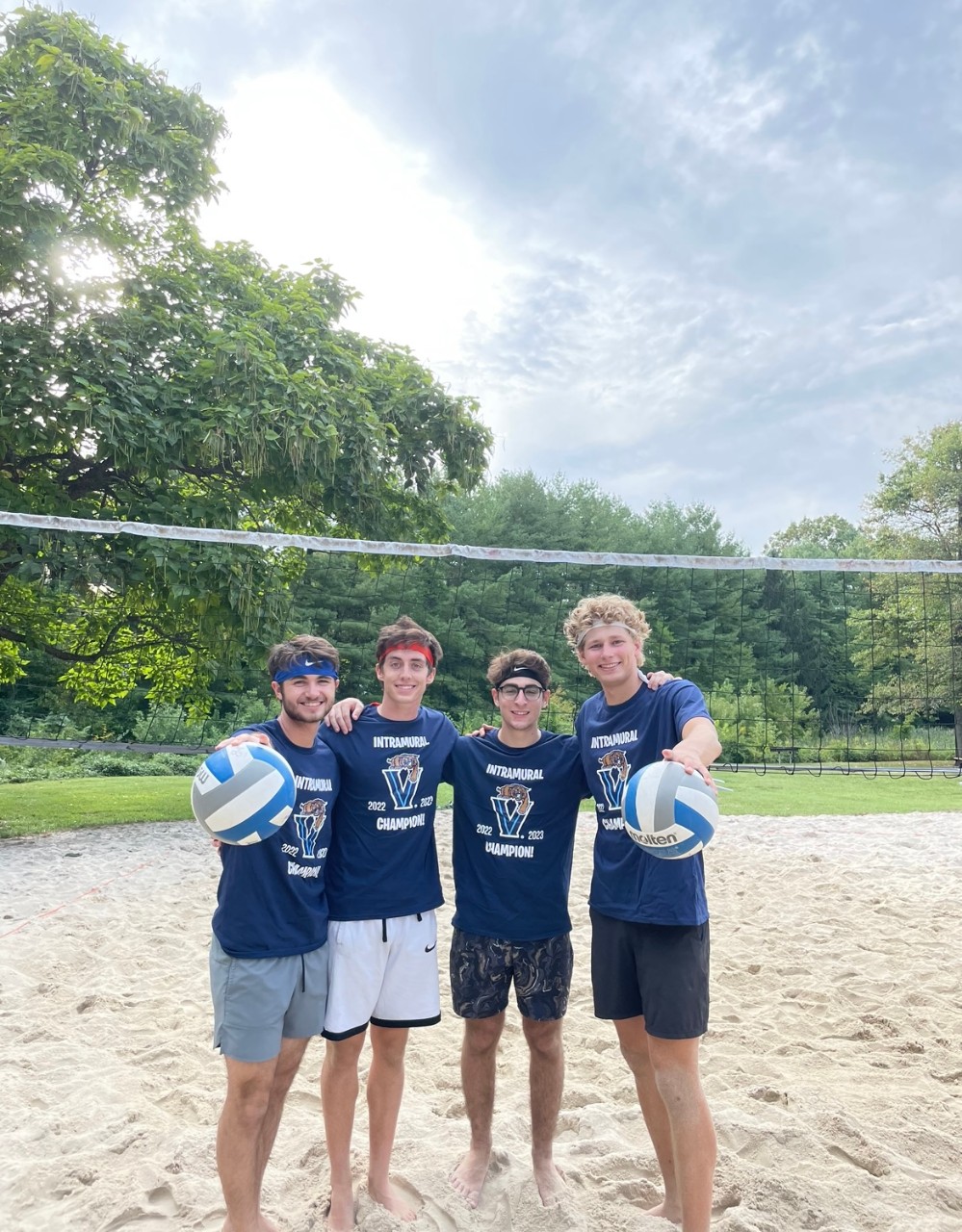Male students posing for sand volleyball champion photo