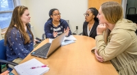 Education graduate students engaged in coversation around a table