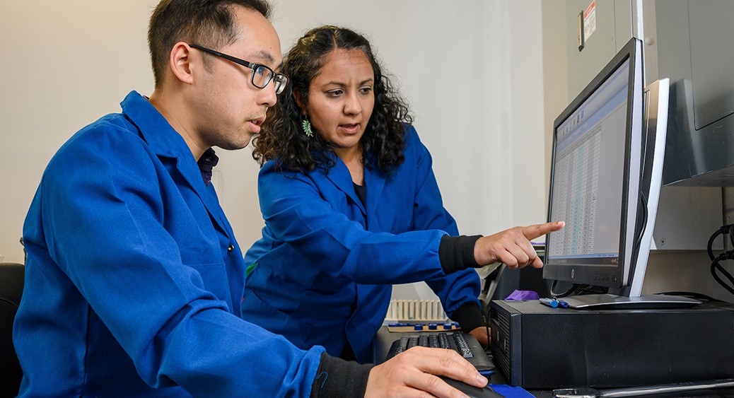 A faculty member instructing a graduate student in a science lab computer terminal