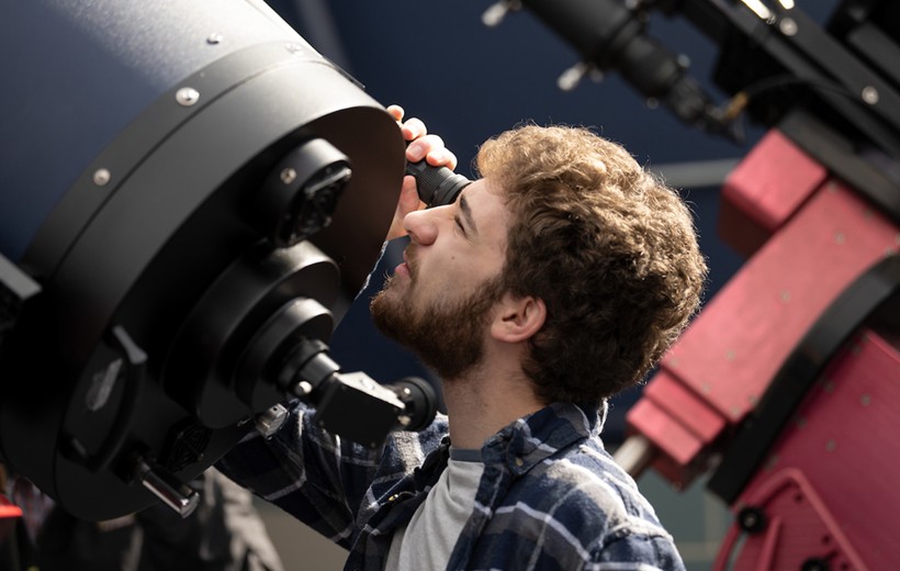 Department of Astrophysics and Planetary Science Student looks through a telescope in the observatory.