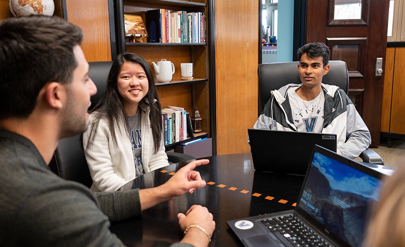 Students discuss around a table. Students around a table.