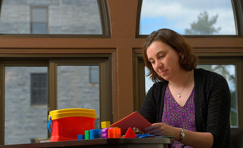 Department of Psychological and Brain Sciences Janette Herbers in front of large window in office reading