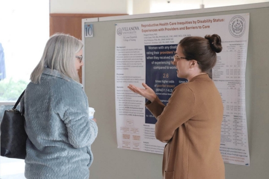 annual-research-symposium A woman giving a presentation to a bystander