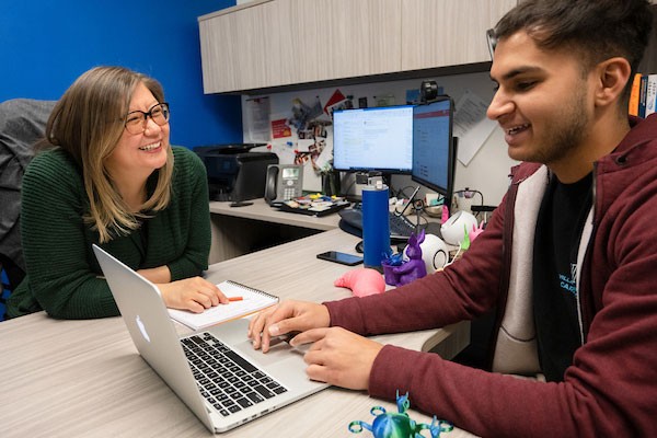 Adviser and student viewing a laptop