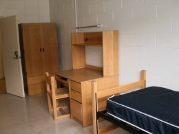 View of a bed, desk and wardrobe in a Delurey Hall room.