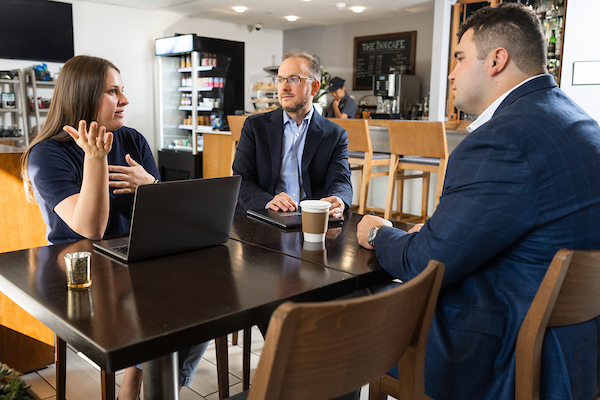three people sitting and talking in a coffee shop