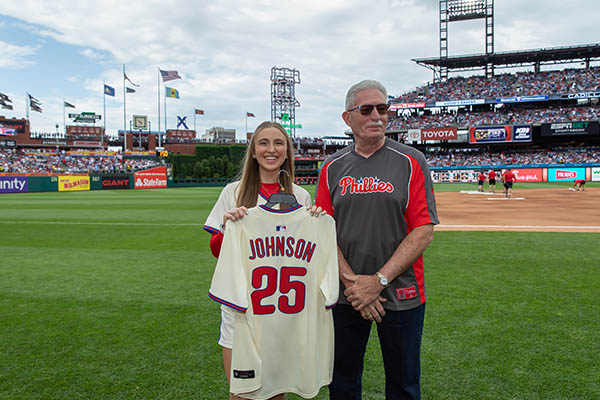 Charles "Chuck" Johnson standing next to a young woman in a Phillies jersey